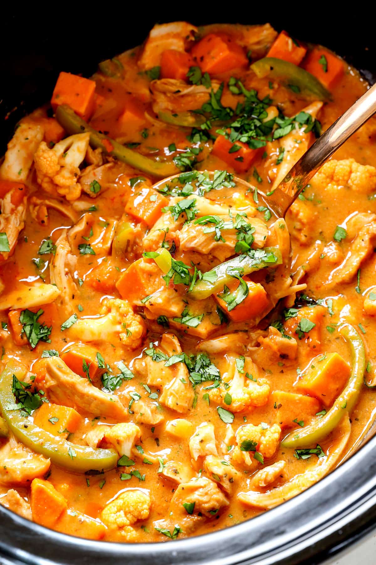 scooping up crockpot curry chicken in the slow cooker showing how creamy it is