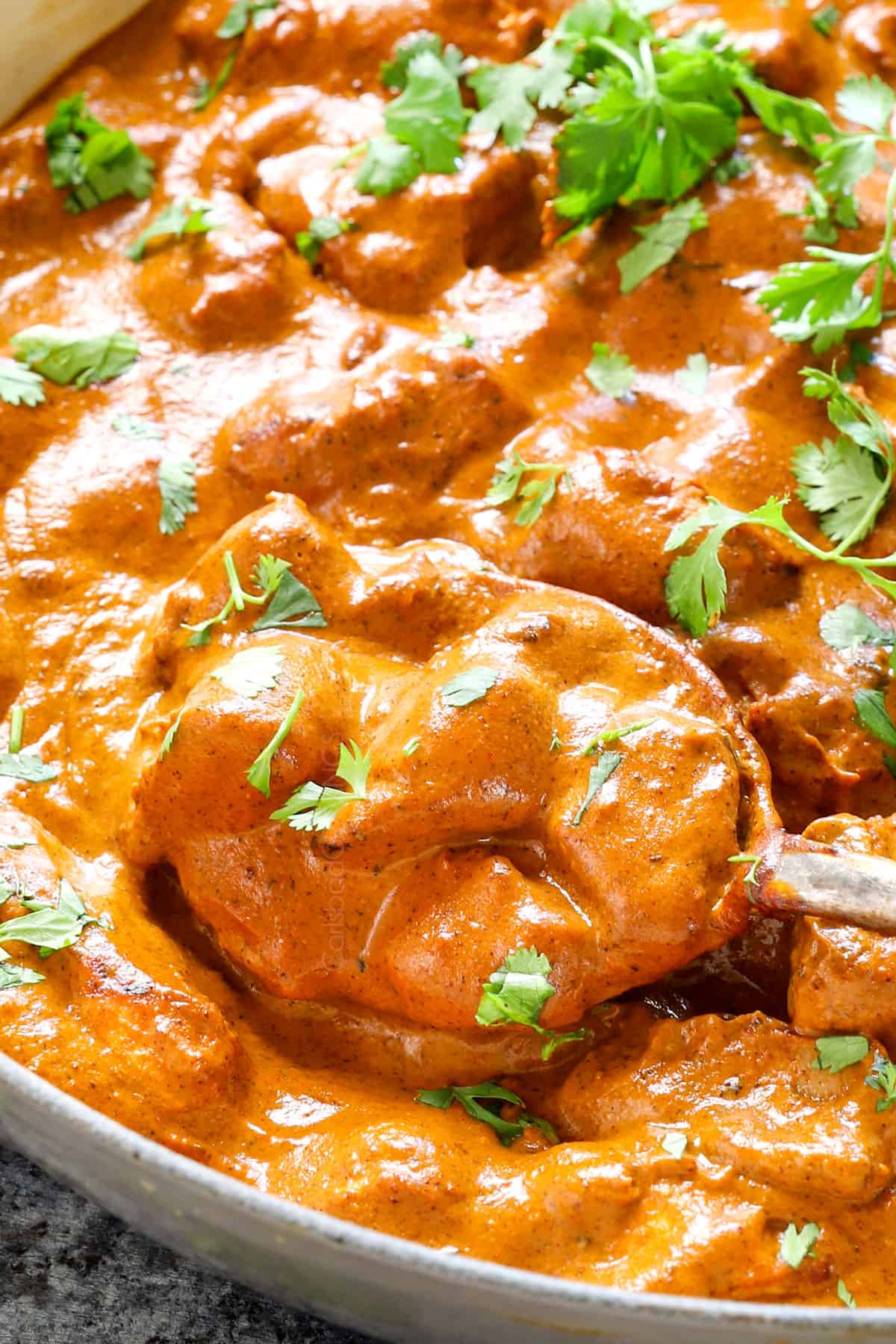 showing how to serve Butter Chicken recipe by garnishing with cilantro