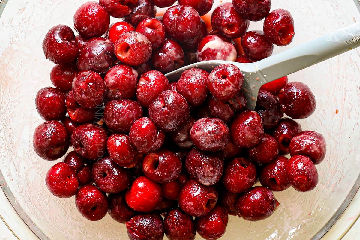 showing how to make cherry crisp by stirring the pitted cherries, granulated sugar, cornstarch, lemon juice, vanilla extract and almond extract together in a large bowl until evenly combined.