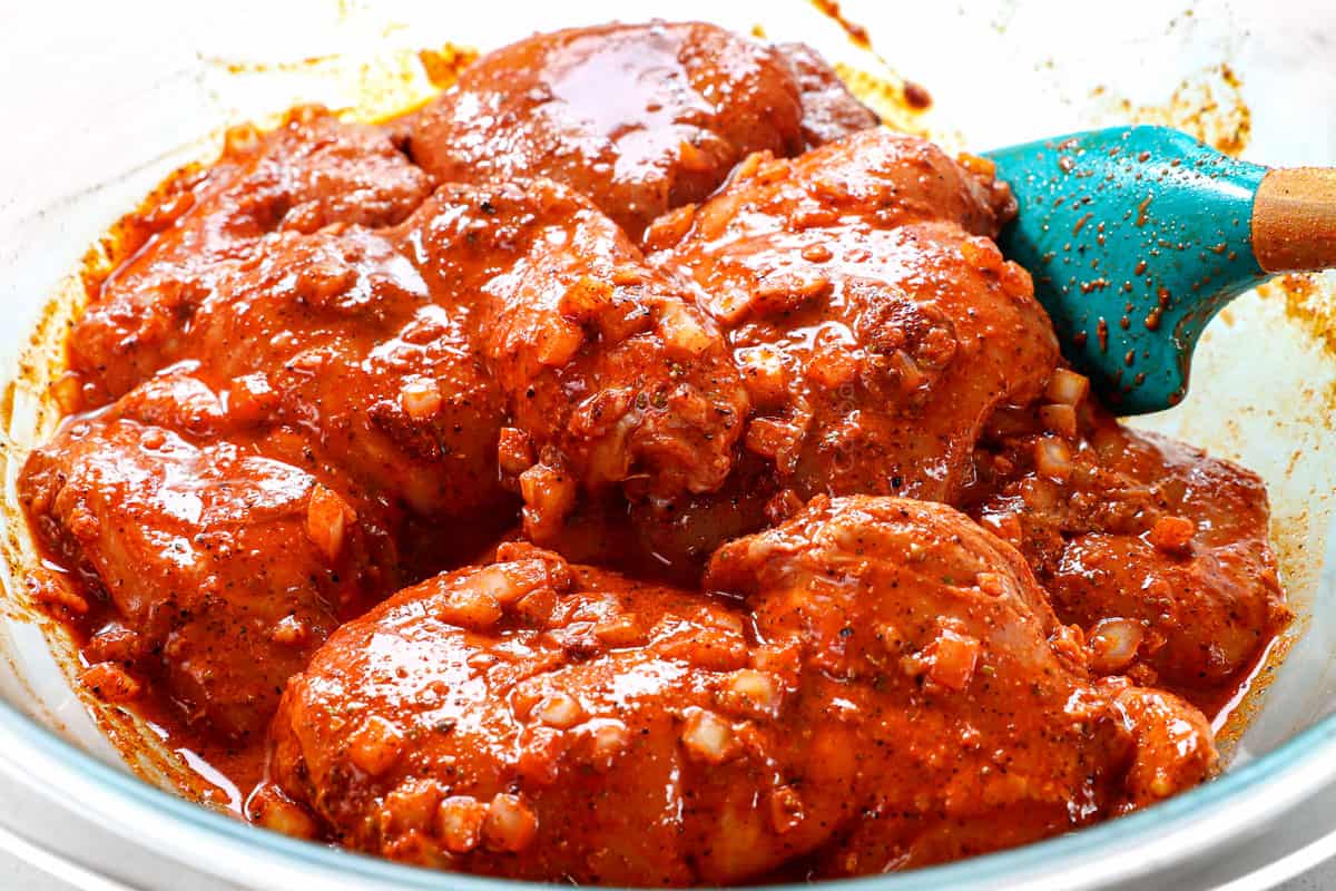 showing how to make chicken street taco recipe by marinating pollo asado with onions, garlic, achiote paste, lime juice and orange juice in a glass bowl