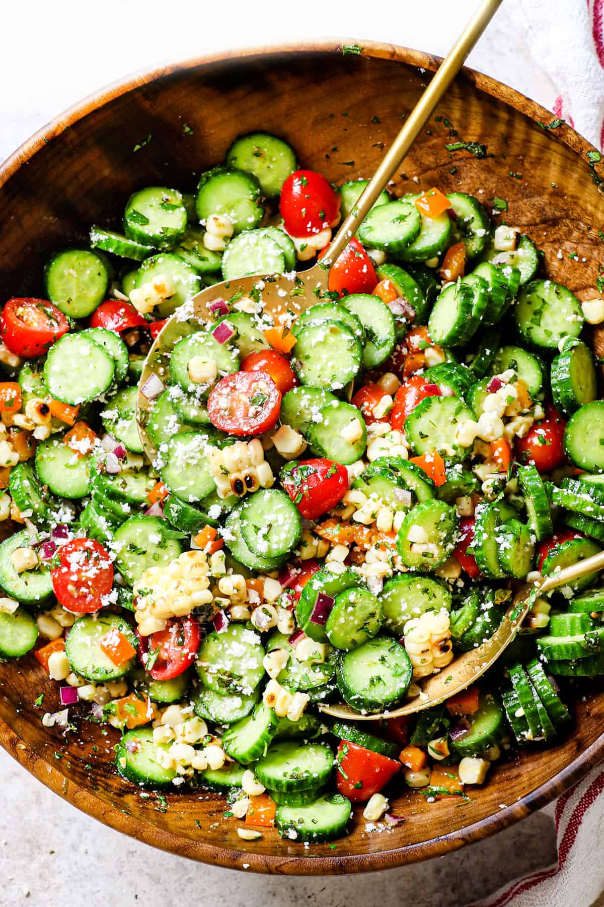 showing how to make cucumber salad by tossing the ingredients together in a bowl with cucumber salad ingredients