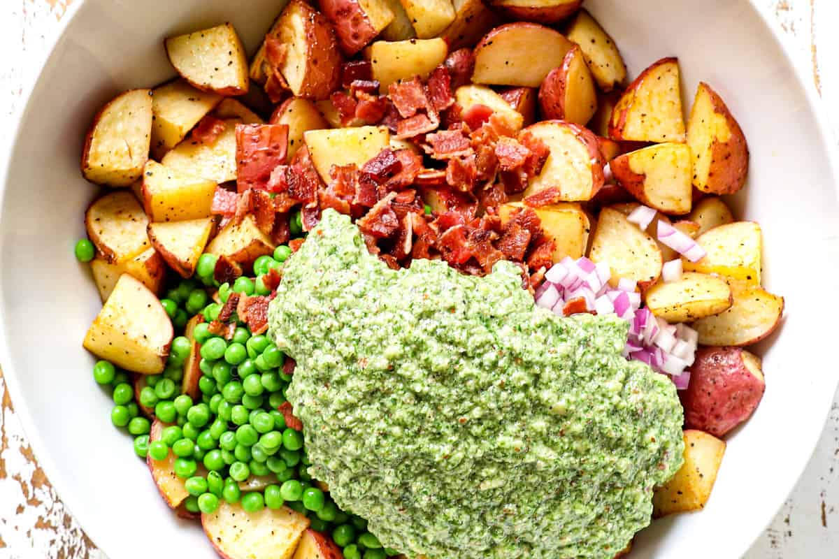 showing how to make red potato salad by adding dressing to red potatoes in a bowl