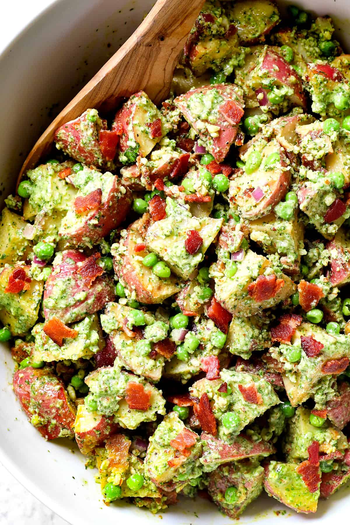 showing how to make red potato salad by tossing the potatoes with the dressing
