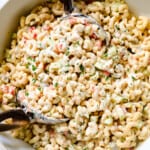showing how to make macaroni salad recipe by tossing the salad dressing with the salad ingredients until creamy