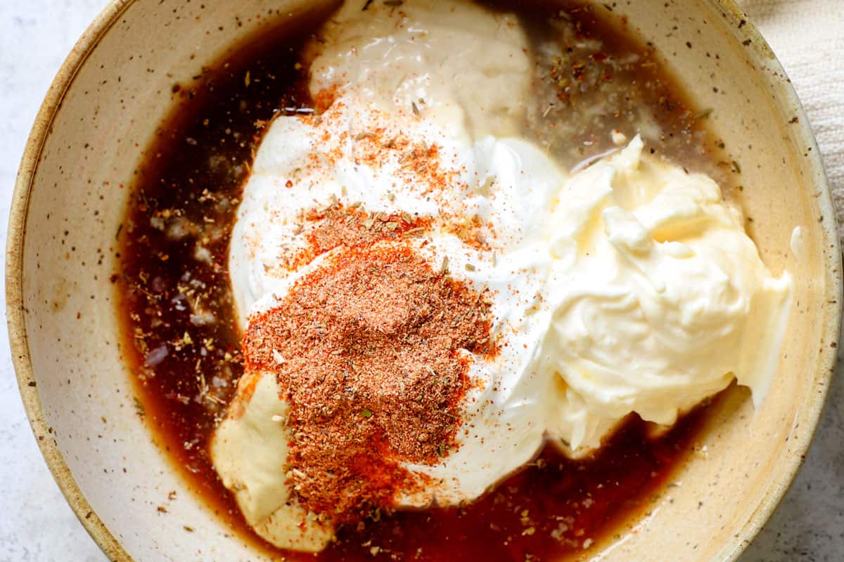 showing how to make remoulade by adding mayonnaise, Greek yogurt, Dijon, Worcestershire, lemon juice, pickle juice and Cajun seasonings to a bowl