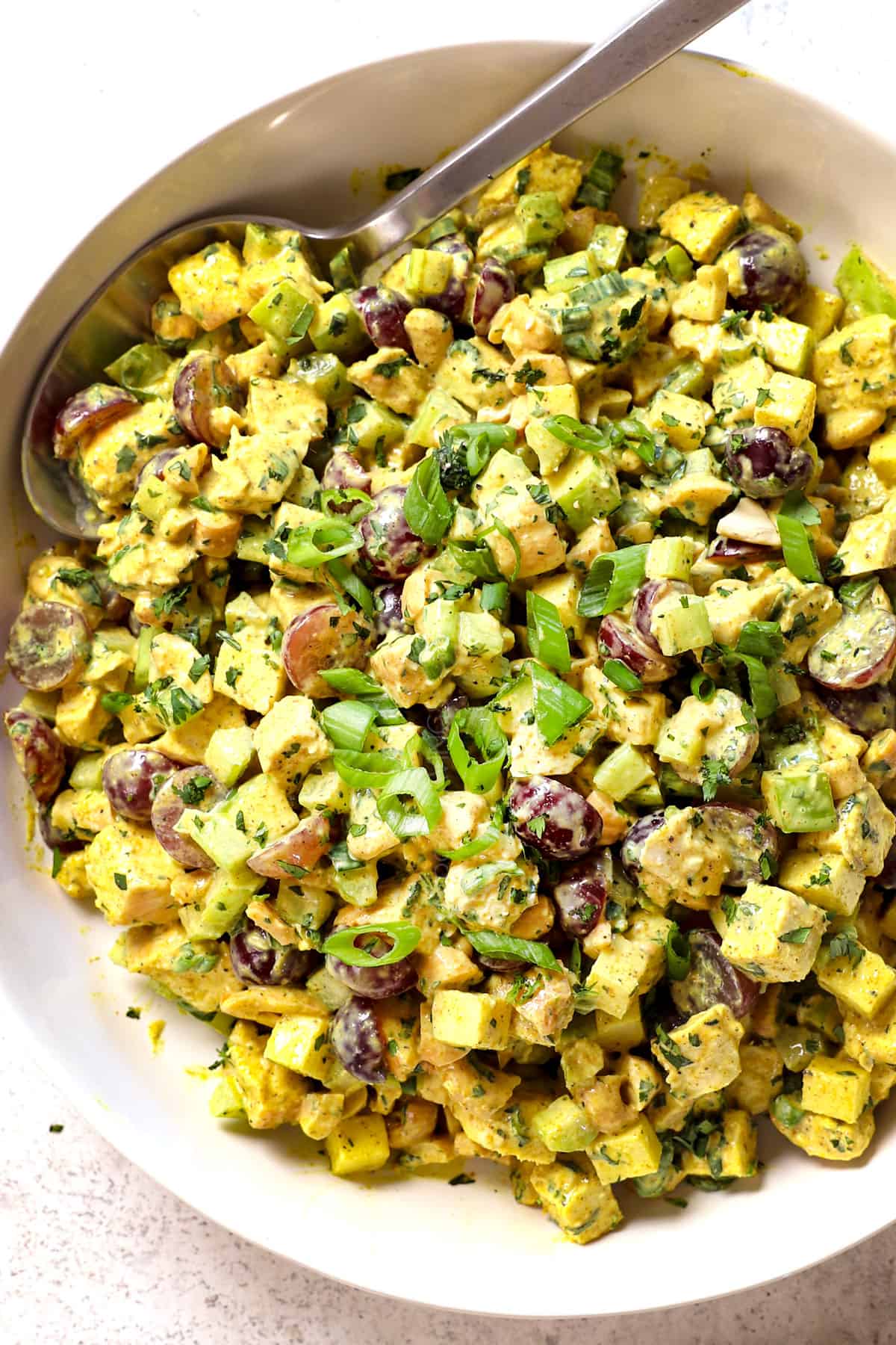 serving chicken curry salad in a bowl garnished by green onions