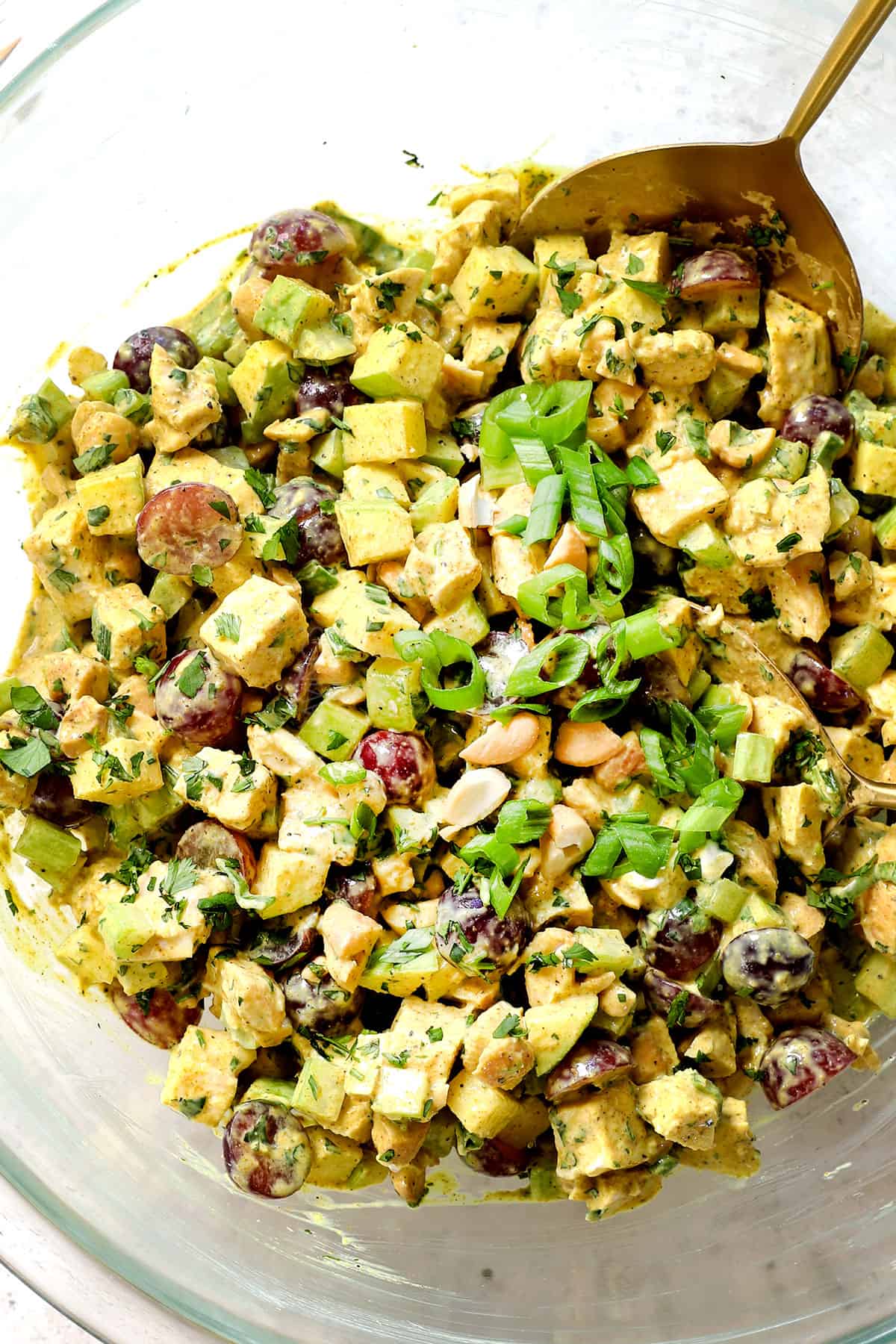 showing how to make curry chicken salad by stirring the dressing and salad ingredients together in a bowl