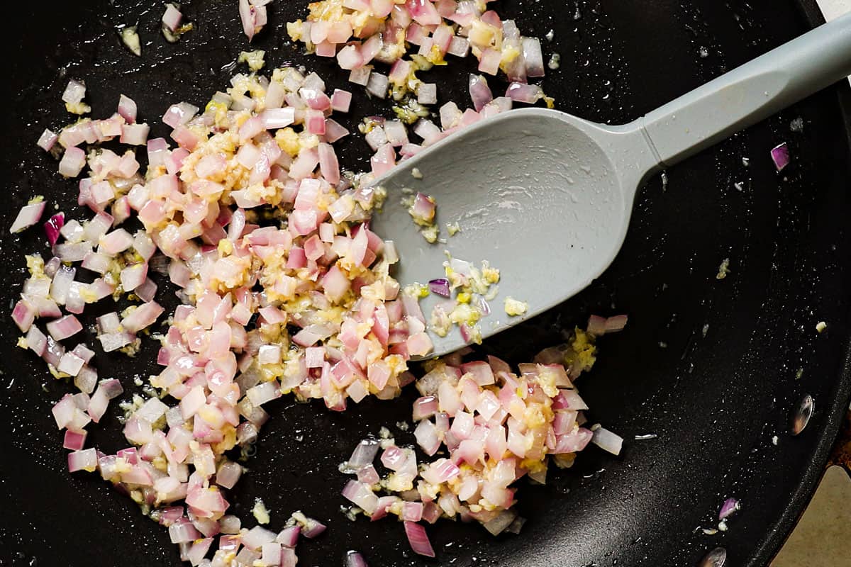 showing how to make chicken pasta salad by sautéing onions and garlic in a pan