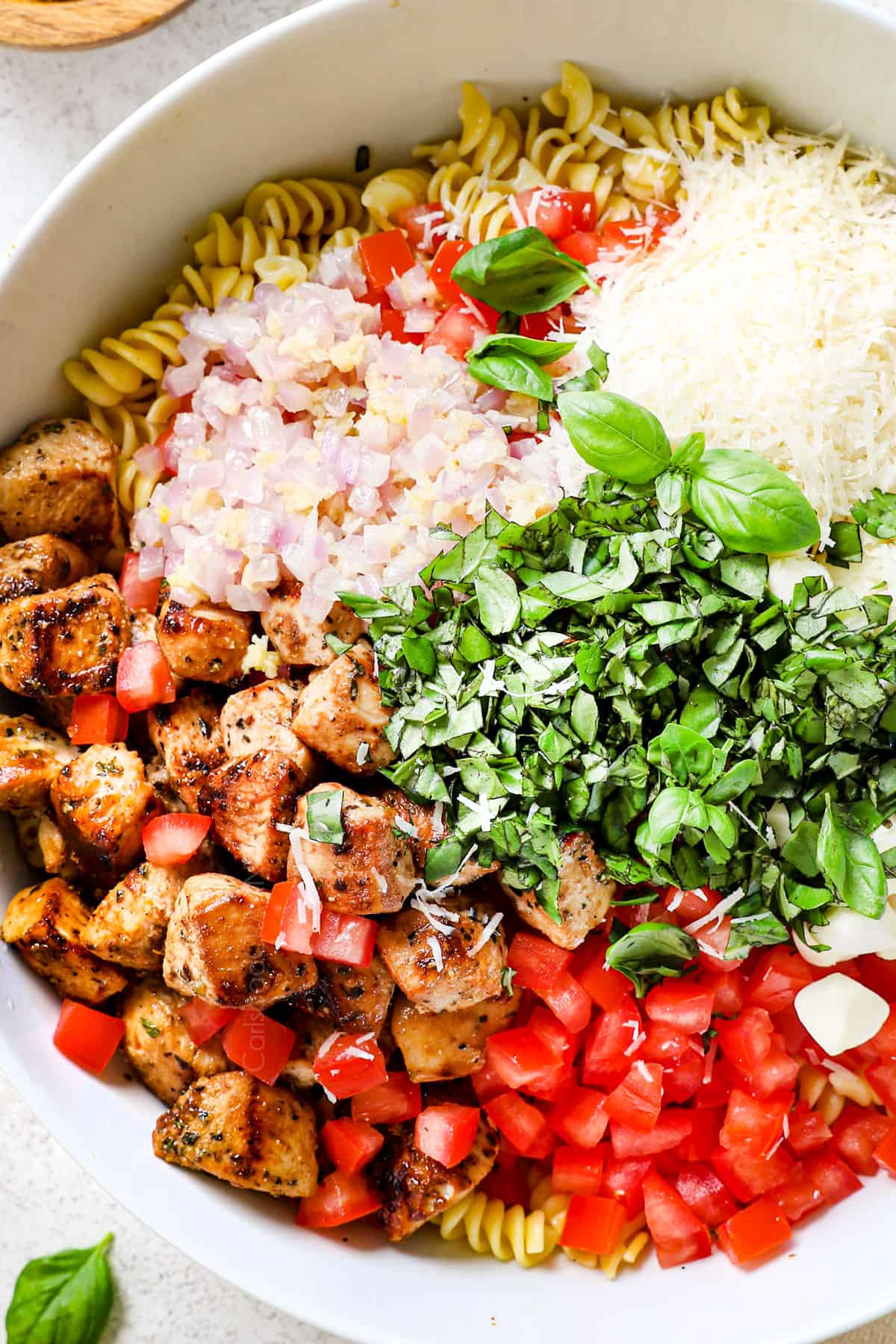 showing how to make chicken pasta salad recipe by tossing pasta salad with dressing