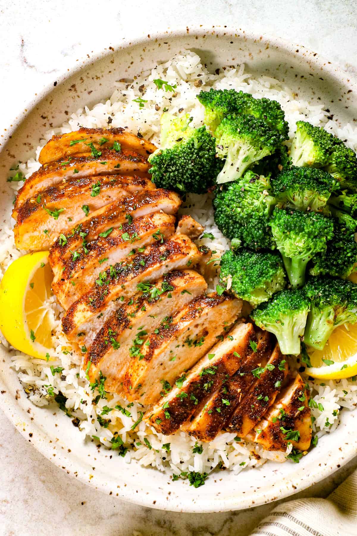 top view of baked boneless chicken breast served in a bowl with broccoli