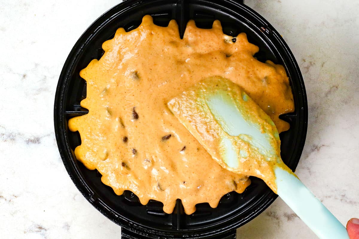 showing how to make pumpkin waffles by adding the batter to the waffle iron