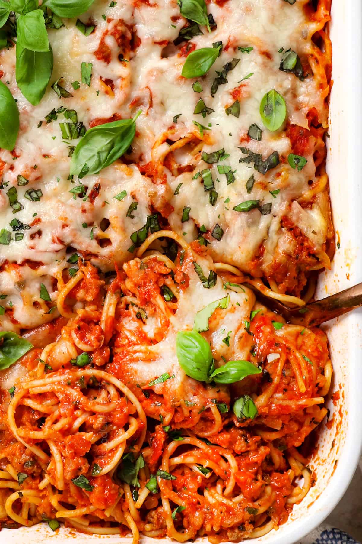 showing how cheesy baked spaghetti recipe is by scooping the casserole up