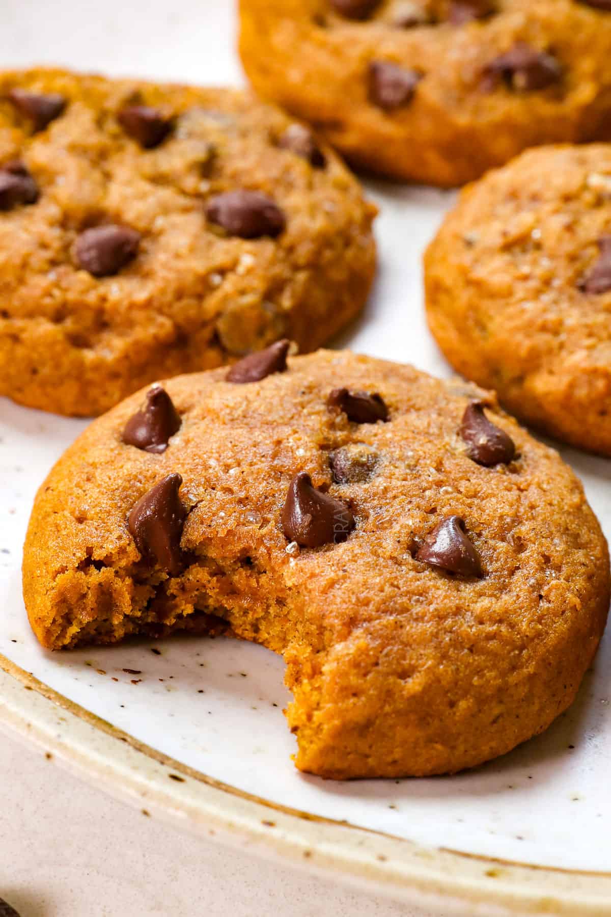 up close of pumpkin chocolate chip cookies recipe with a bite taken out showing how soft it is