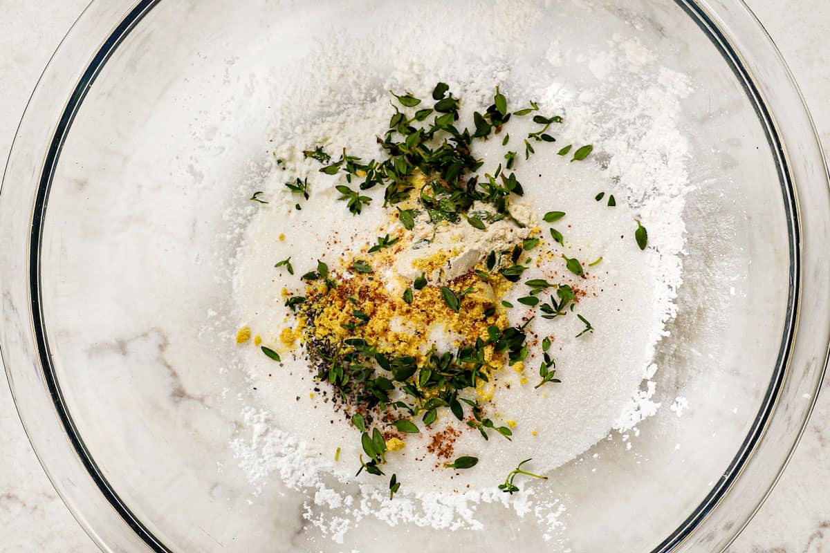 showing how to make corn pudding by mixing sugar, cornstarch, herbs and seasonings together in a bowl