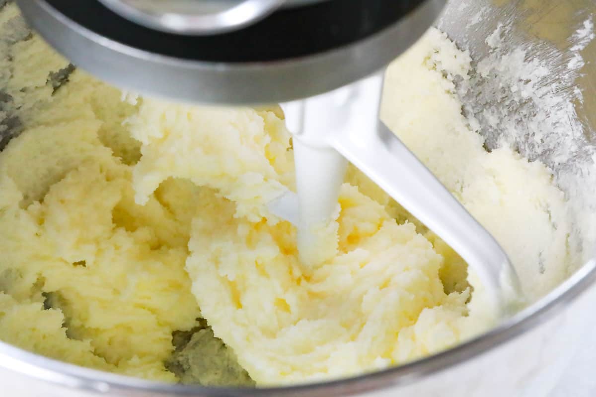 showing how to make sugar cookies by creaming butter and sugar in a stand mixer until light and fluffy