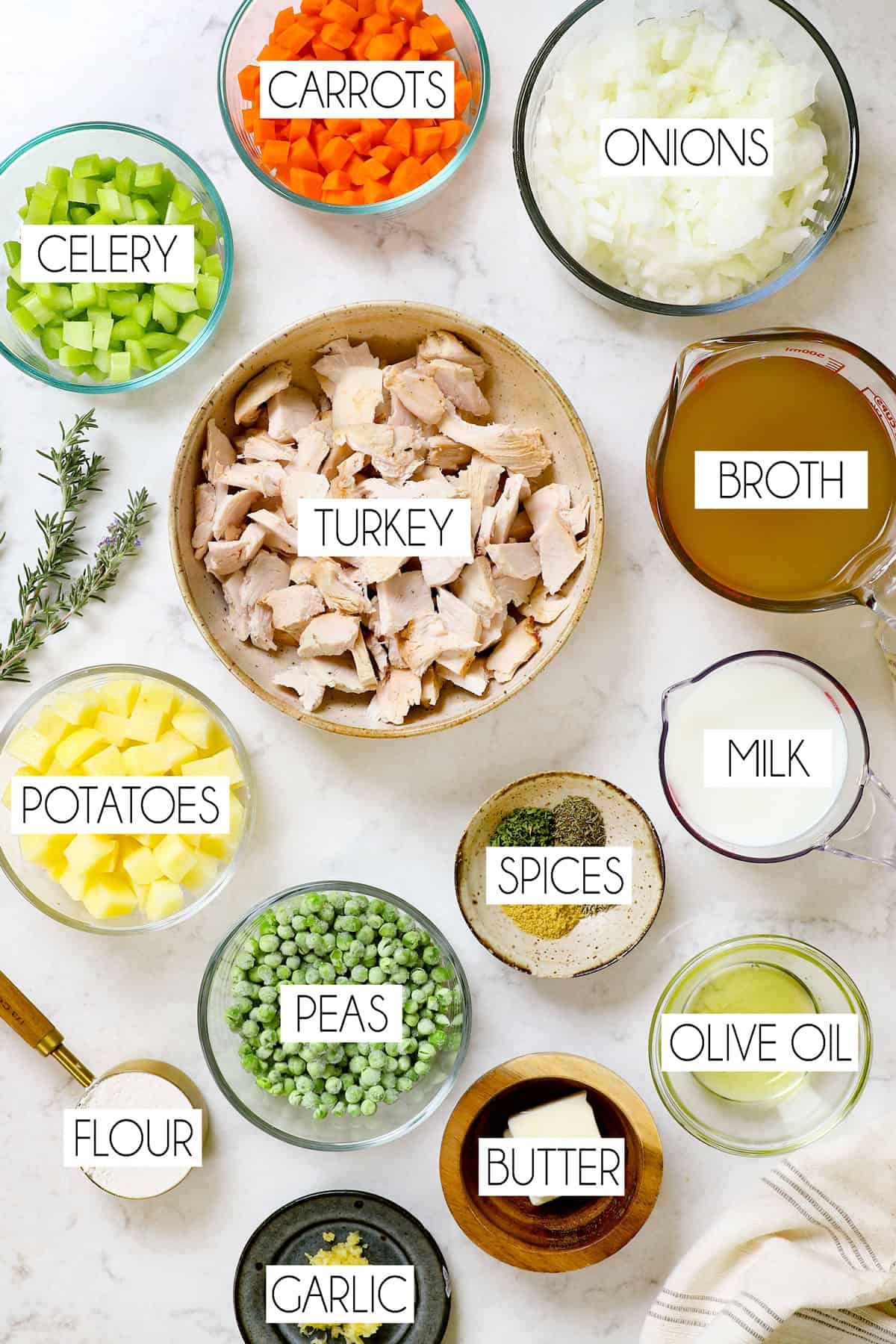top view of ingredients for turkey pot pie: turkey, potatoes, celery, carrots, chicken broth, flour, garlic, onions and spices