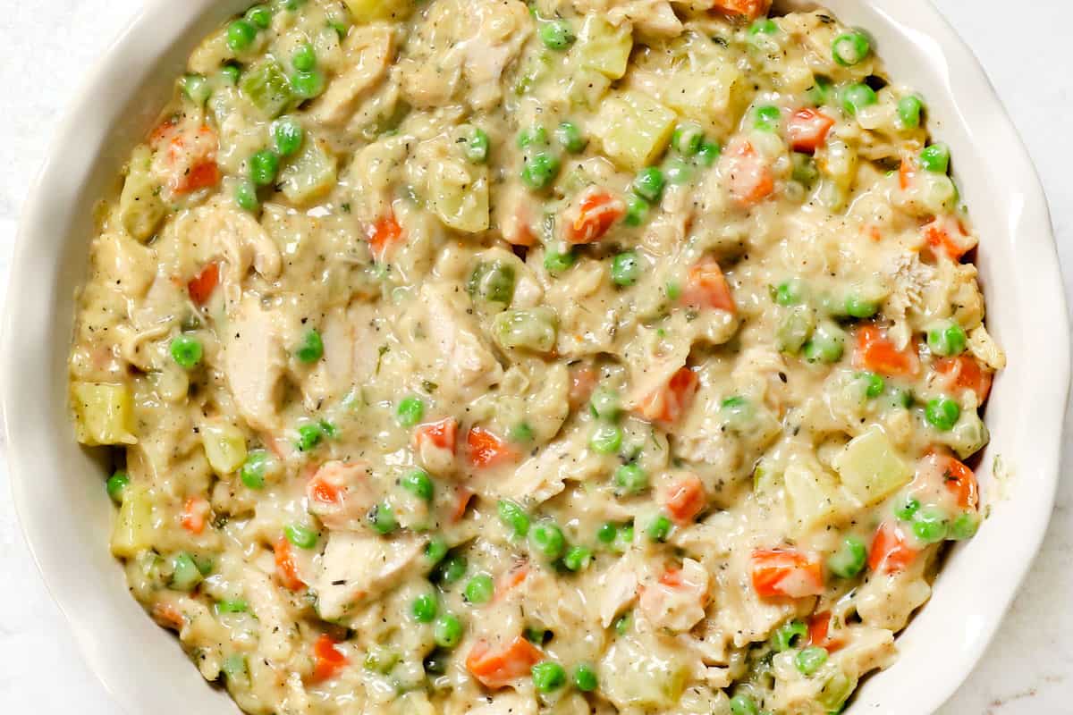 showing how to make turkey pot pie by adding filling to the pie plate