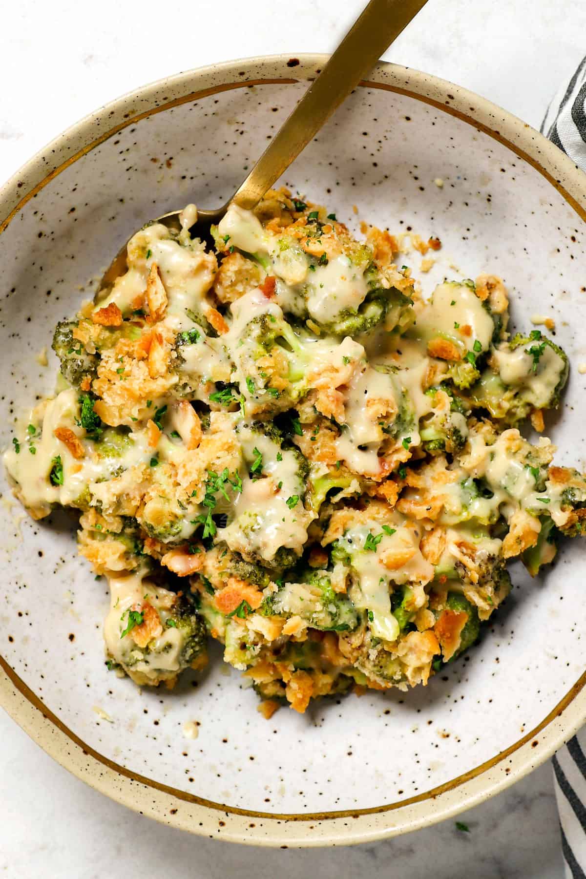 showing how to serve broccoli and cheese casserole on a plate garnished by parsley