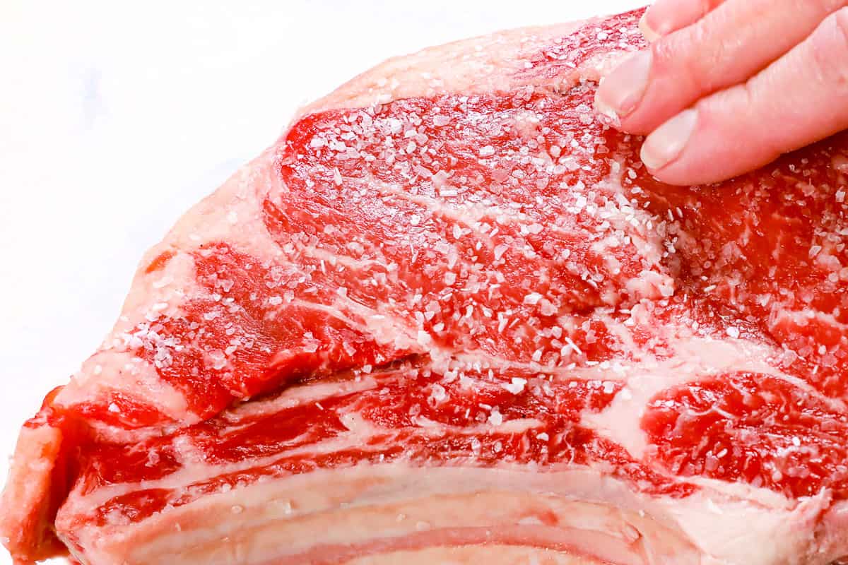 showing how to cook prime rib by adding kosher salt to dry brine