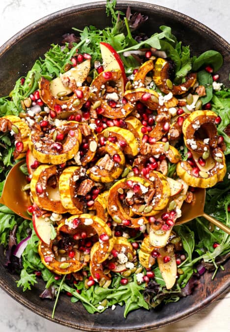 showing how to make squash salad by layering lettuce with red onions, apples, squash, feta, pepitas, and feta