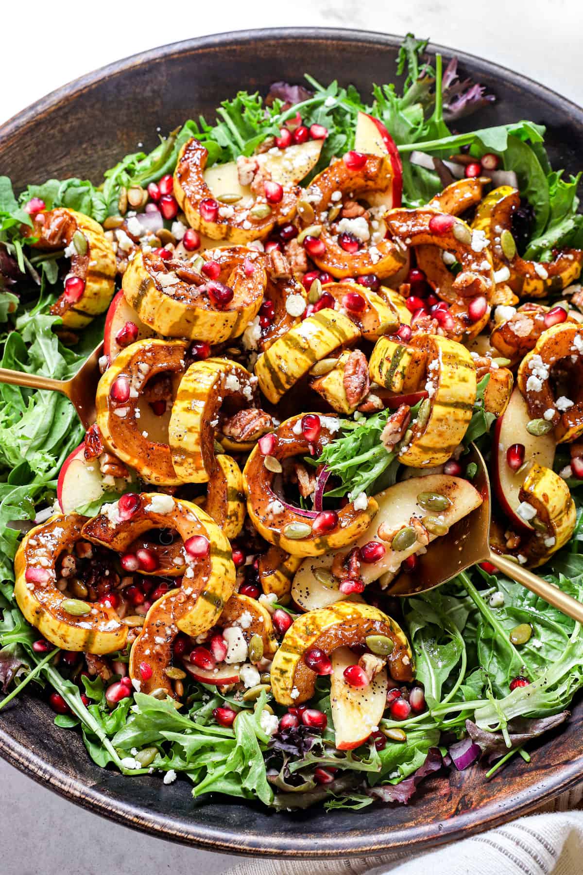 showing how to make winter salad by tossing all the ingredients with the dressing in a salad bowl
