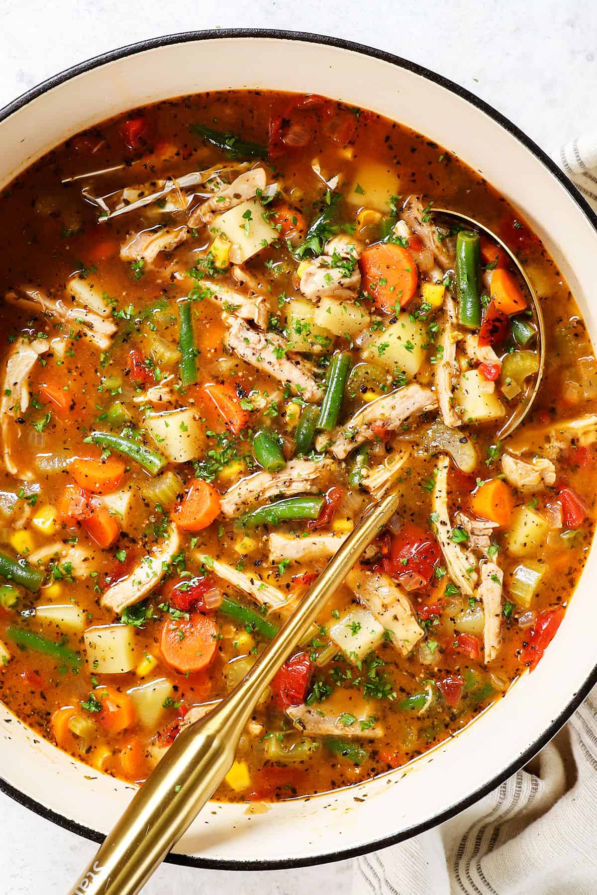 top view of chicken vegetable soup recipe with a ladle in the soup showing how chunky with vegetables it is