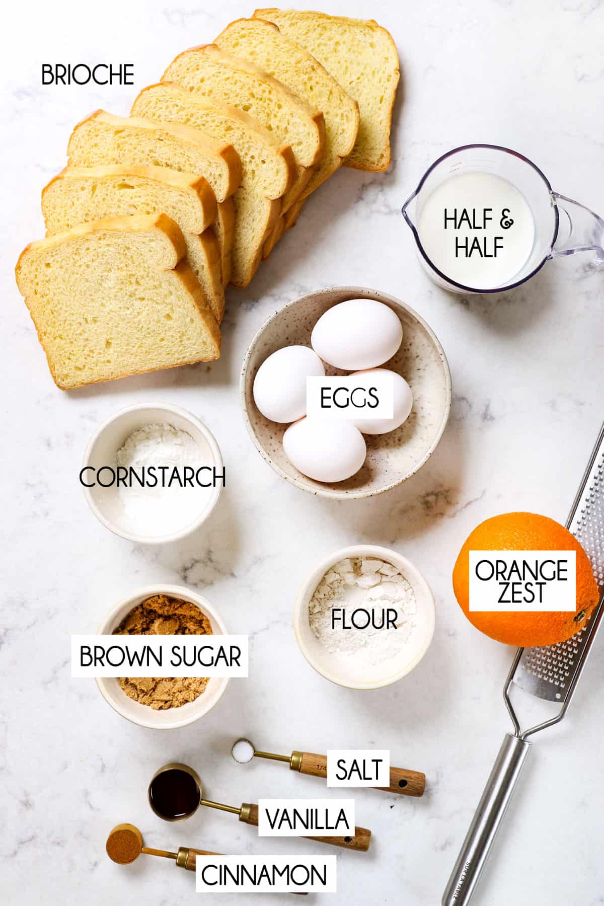 showing ingredients for French toast lined up: brioche bread, eggs, half and half, flour, vanilla extract, salt, nutmeg and orange zest