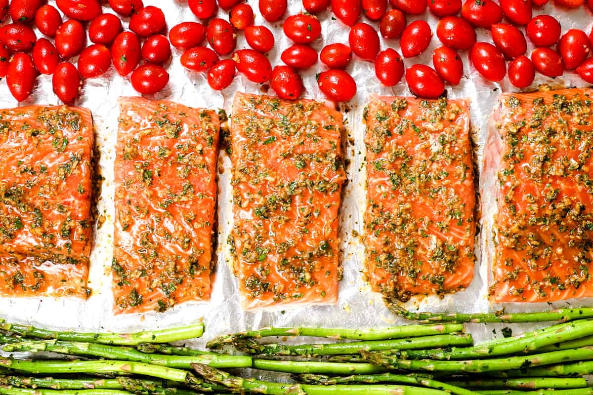 showing how to make baked salmon in the oven by adding wet rub to salmon fillets to marinate