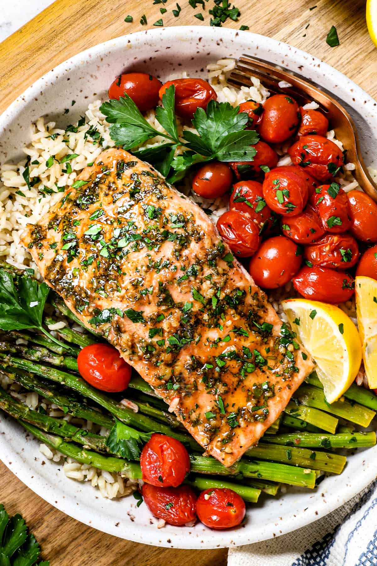 top view showing how to serve baked salmon in oven on a plate with rice, tomatoes and asparagus