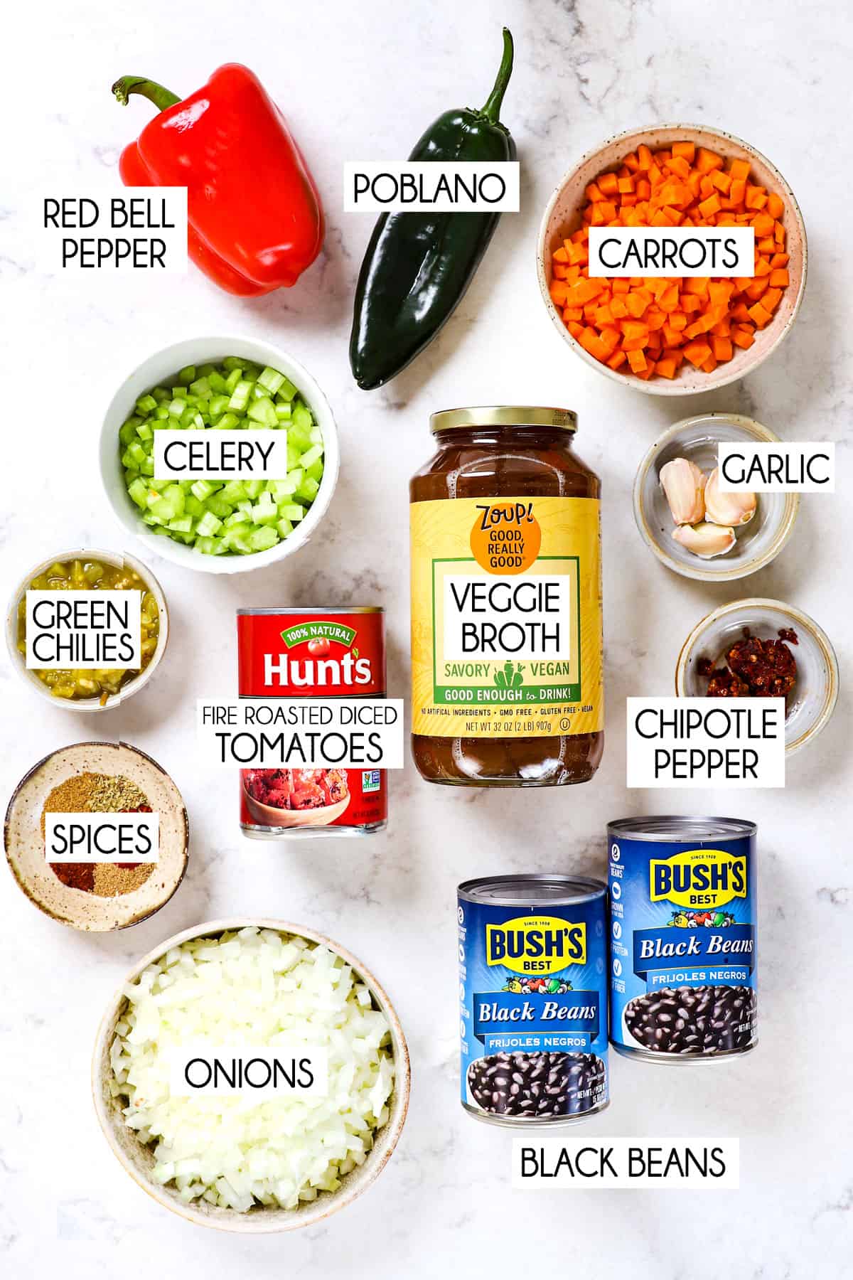 top view showing ingredients to make black bean soup: black beans, vegetable broth, diced tomatoes, carrots, celery, onions, garlic, spices and chipotle pepper