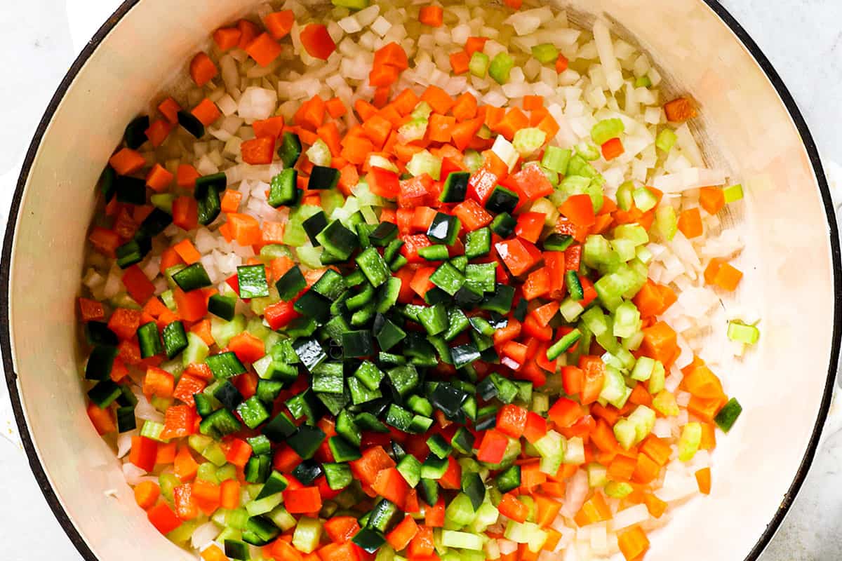 showing how to make black bean soup by sautéing onions, celery, carrots, and bell pepper