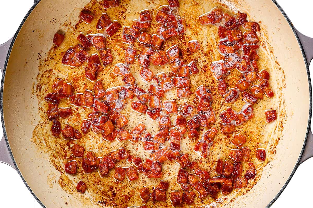 showing how to make colcannon by cooking bacon until crispy in a pan
