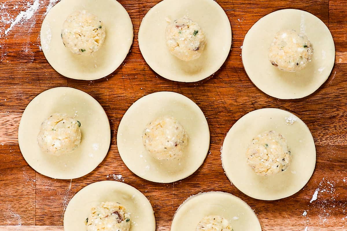 showing how to make pierogi by adding pierogi filling to the pierogi dough cut in circles