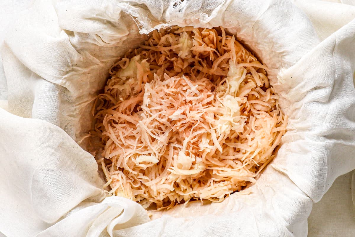 showing how to make potato pancakes by draining excess liquid with cheesecloth
