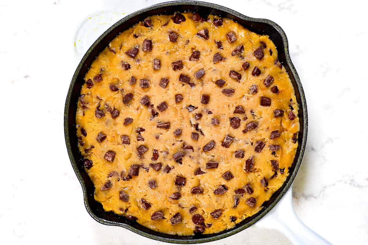 showing how to make pizookie by adding dough to a skillet and pressing into an even layer