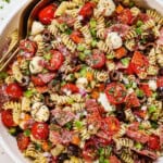 top view of pasta salad recipe in a bowl with salami, tomatoes, bell peppers, olives, pepperoncini, Parmesan and parsley