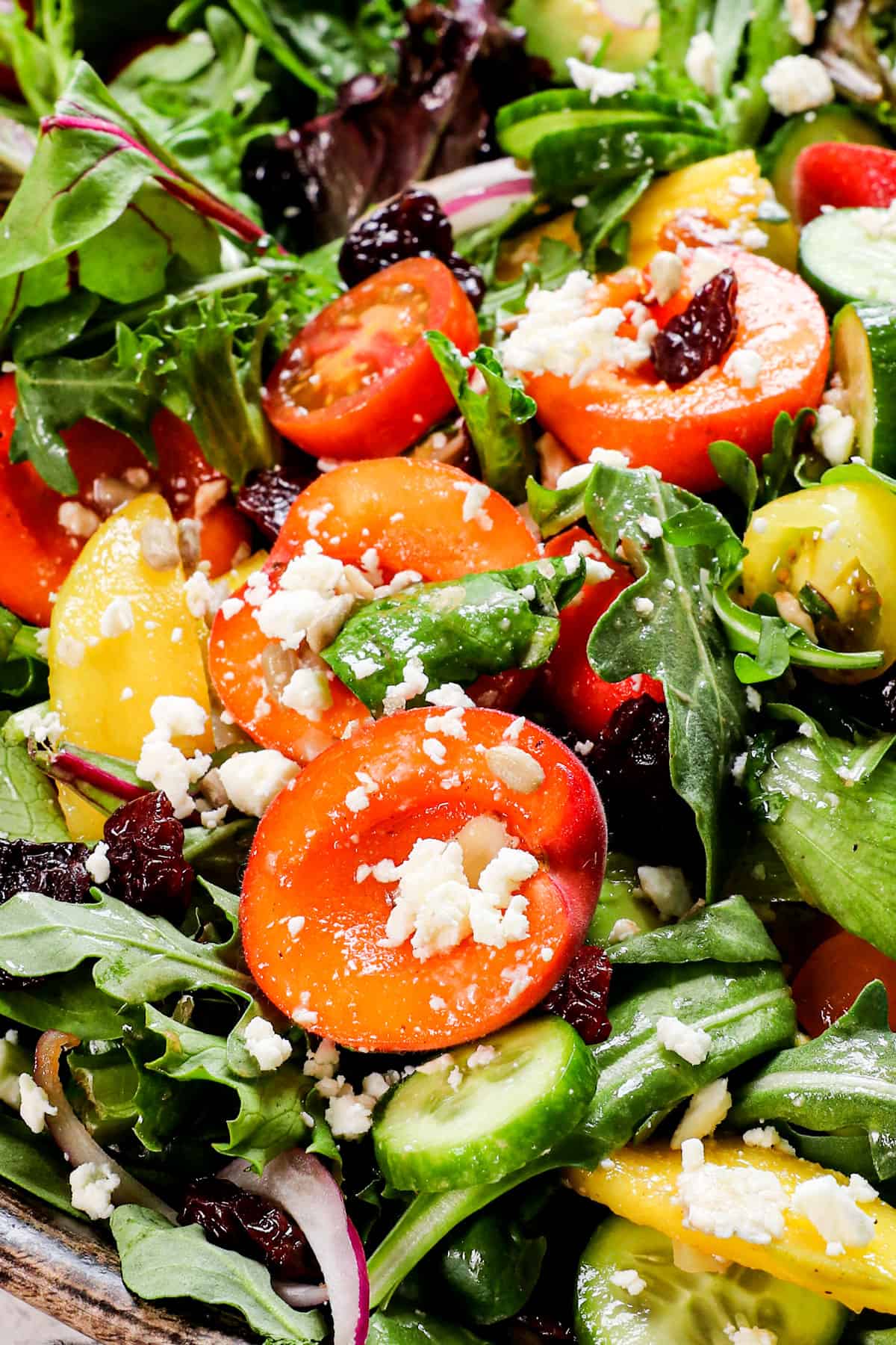 showing how to make summer salad by tossing the salad together with tongs