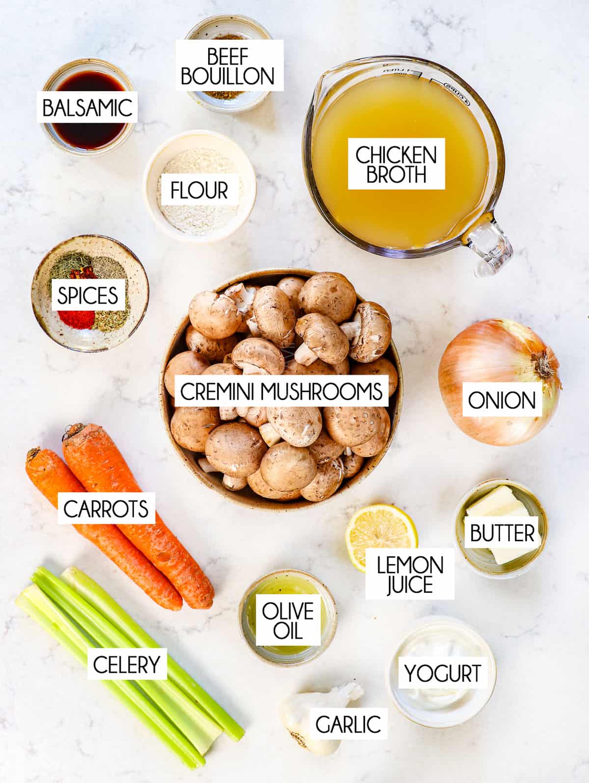 top view showing ingredients for mushroom soup: cremini mushrooms, chicken broth, onion, garlic, celery, carrots, spices, flour, balsamic, and lemon juice