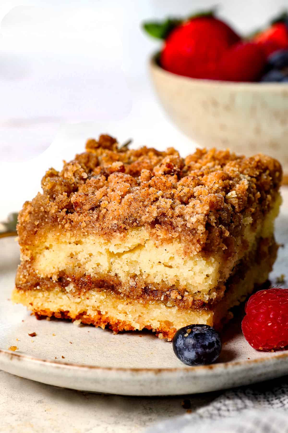 a slice of cinnamon streusel coffee cake on a plate served with berries