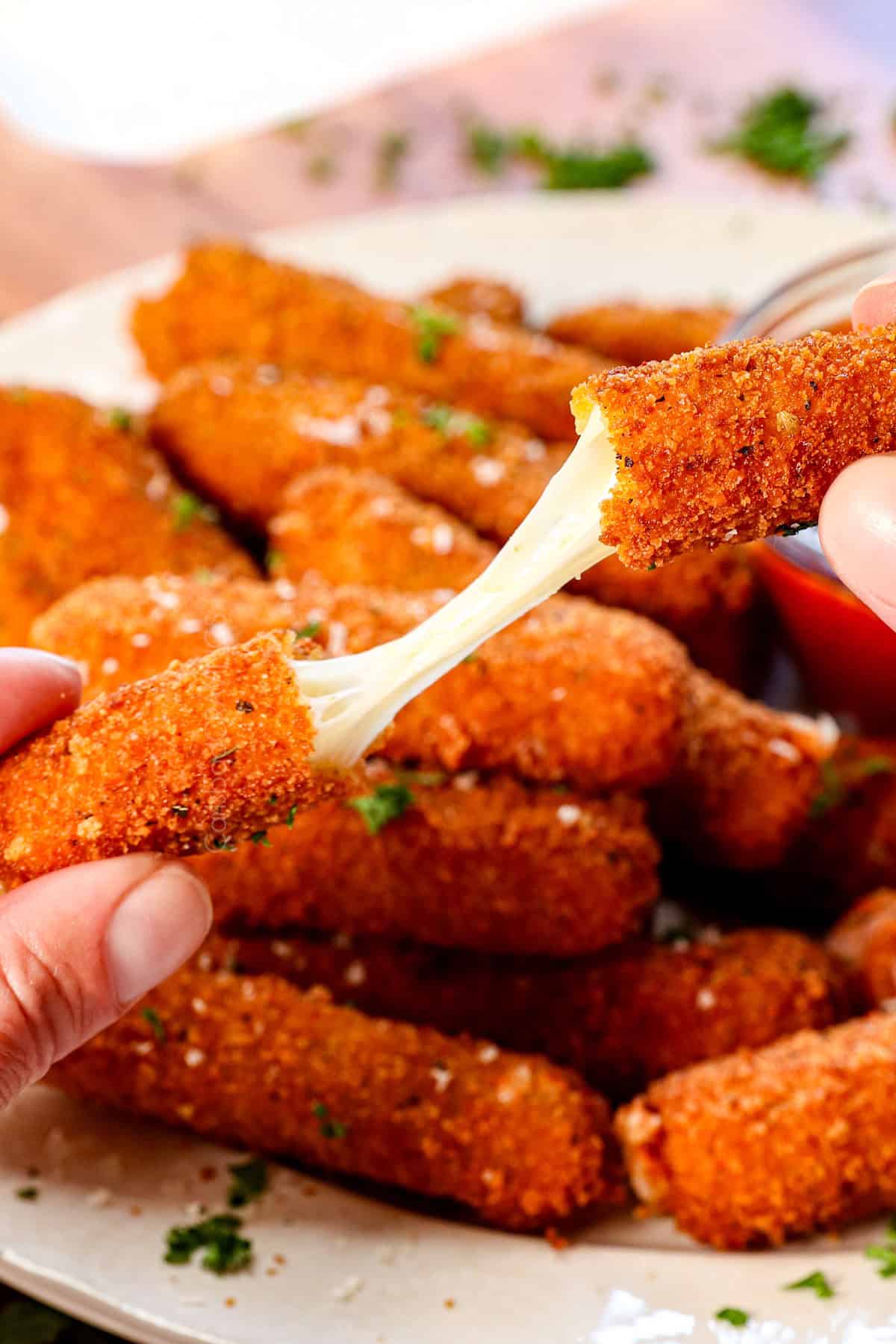 showing how cheesy the mozzarella cheese sticks are by pulling a cheese stick apart