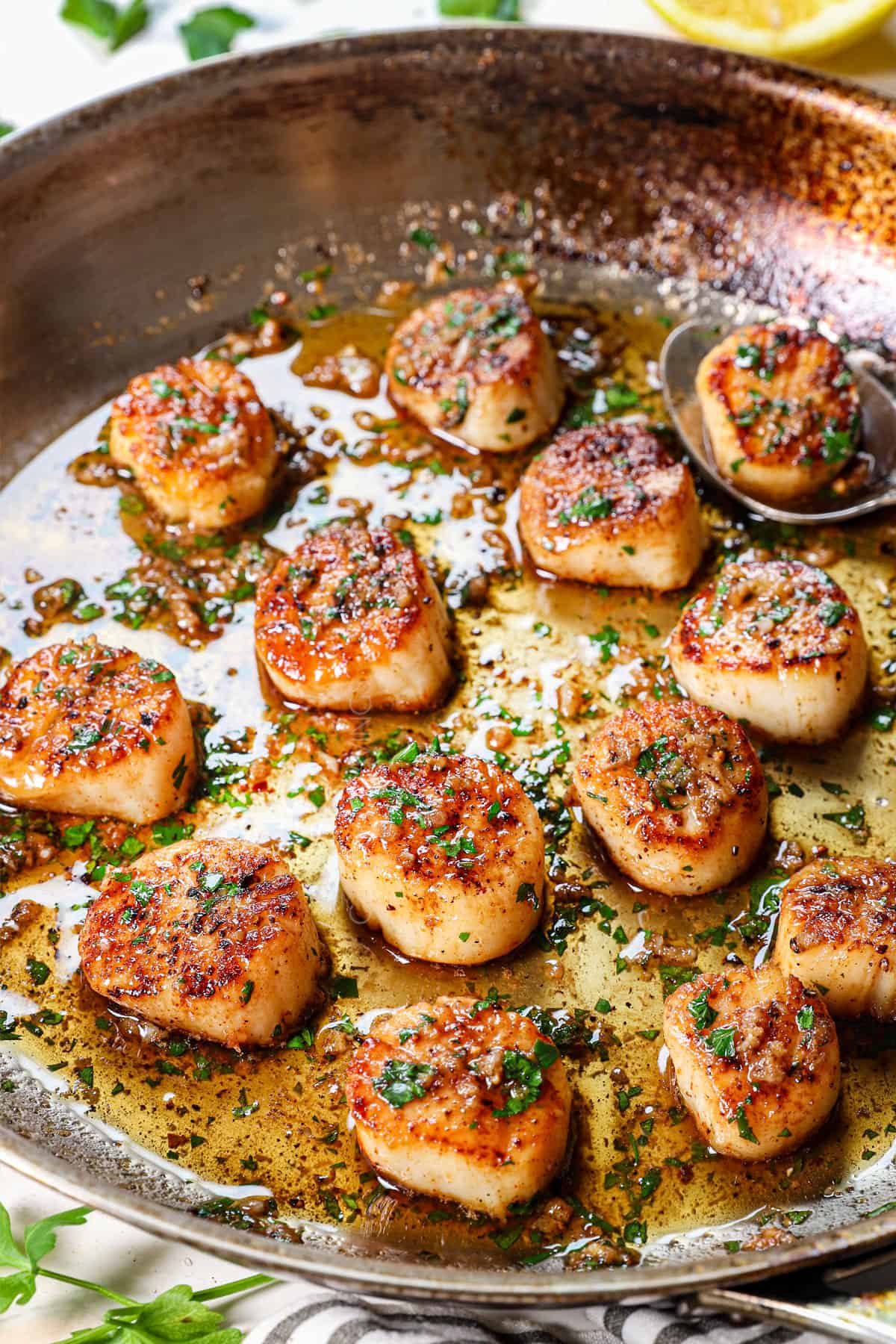 showing how to make pan seared scallops by drizzling with lemon garlic butter sauce
