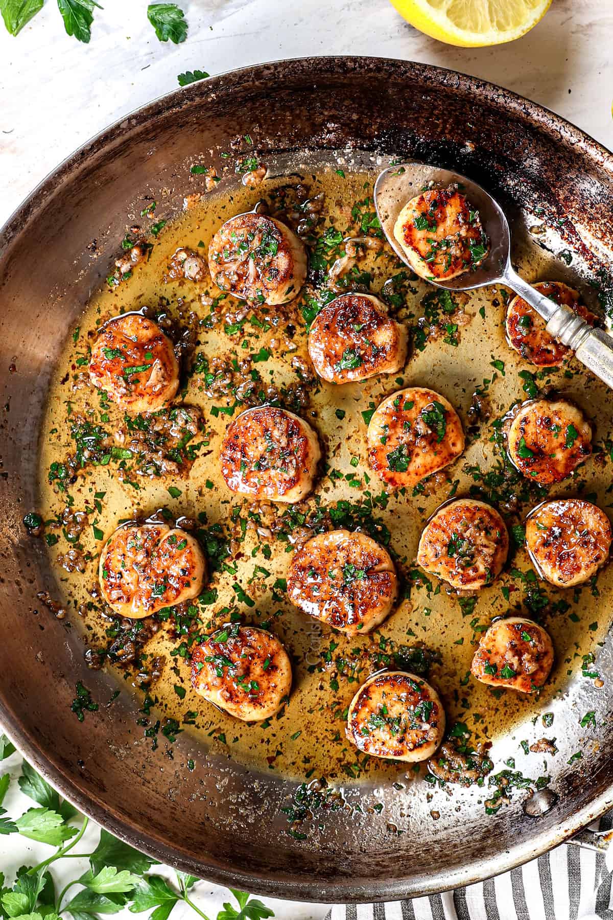 top view of scallops in a pan with butter, lemon, garlic and parsley