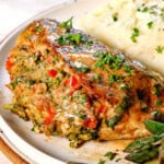 up close of serving baked stuffed chicken breast on a plate with mashed potatoes and asparagus