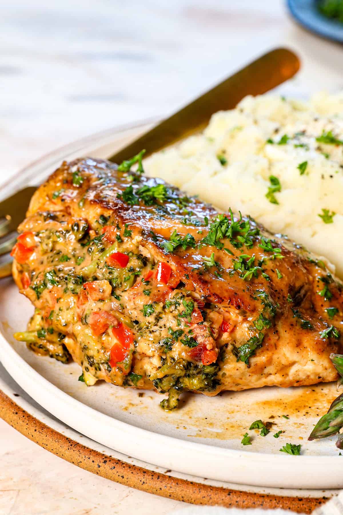 up close of serving baked stuffed chicken breast on a plate with mashed potatoes and asparagus