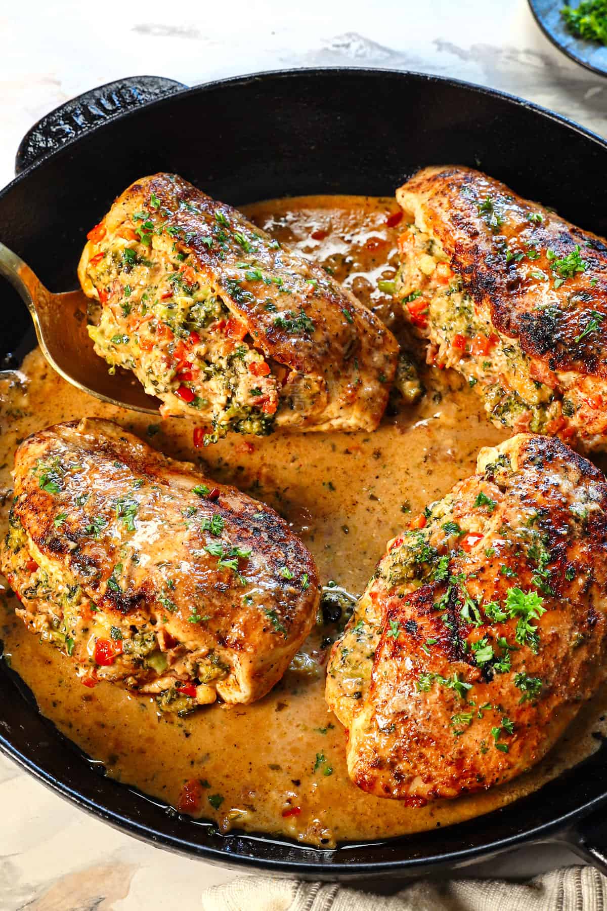 broccoli and cheese stuffed chicken breast in a skillet with a pan sauce