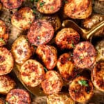 top view of scooping up roast potatoes on a baking sheet showing their crispiness