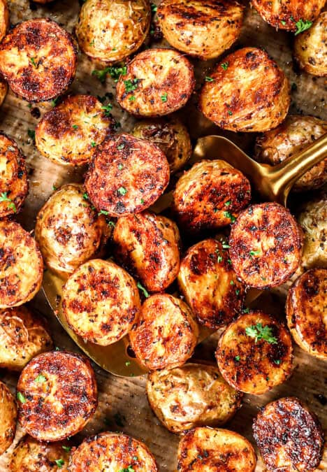 top view of scooping up roast potatoes on a baking sheet showing their crispiness