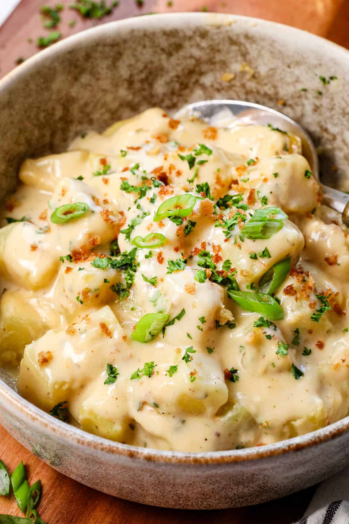 up close of recipe for cheesy potatoes in a bowl showing how cheesy and creamy they are