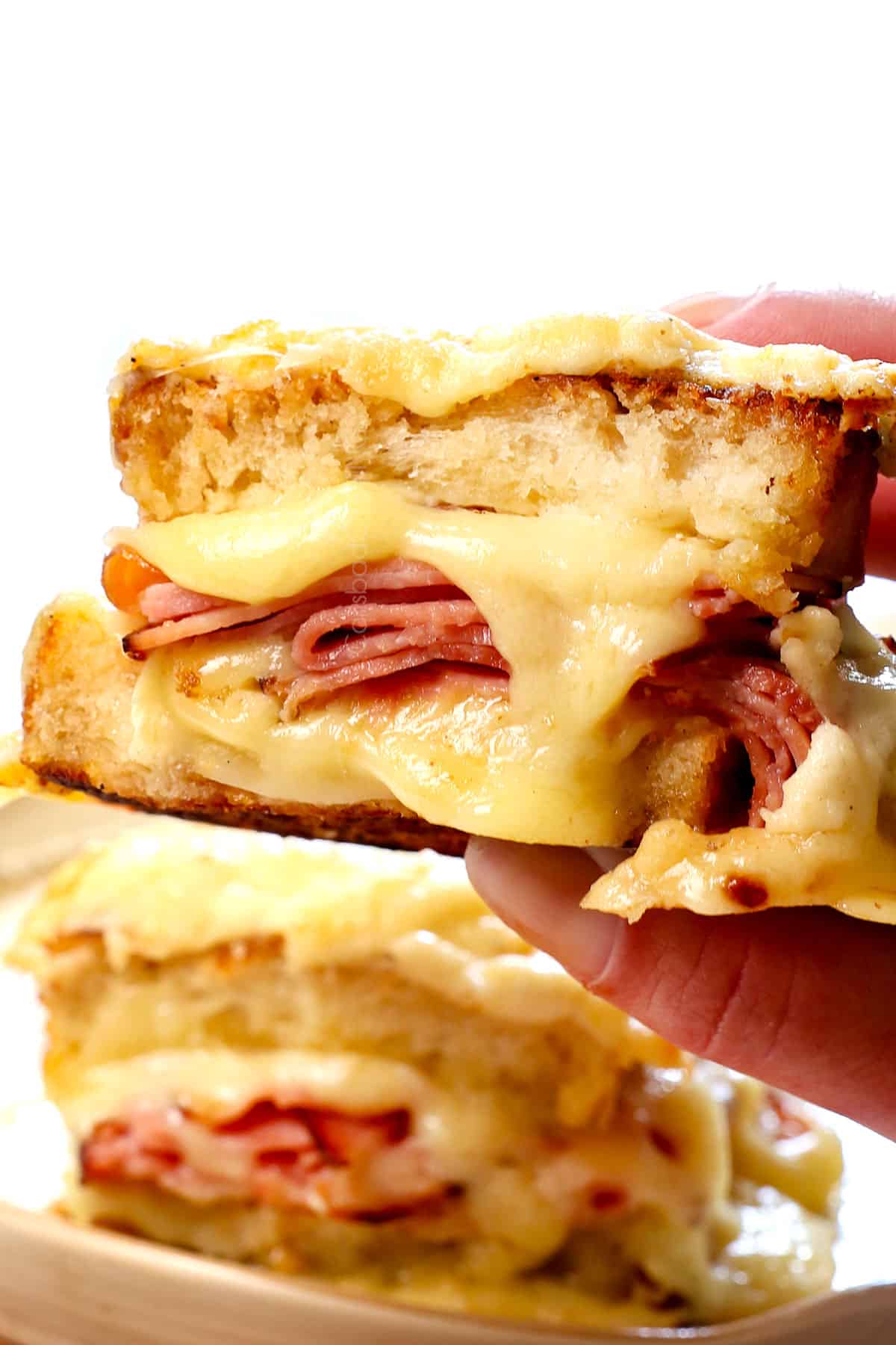 up close of holding croque monsieur showing the thick bread, ham slices, and melty cheese