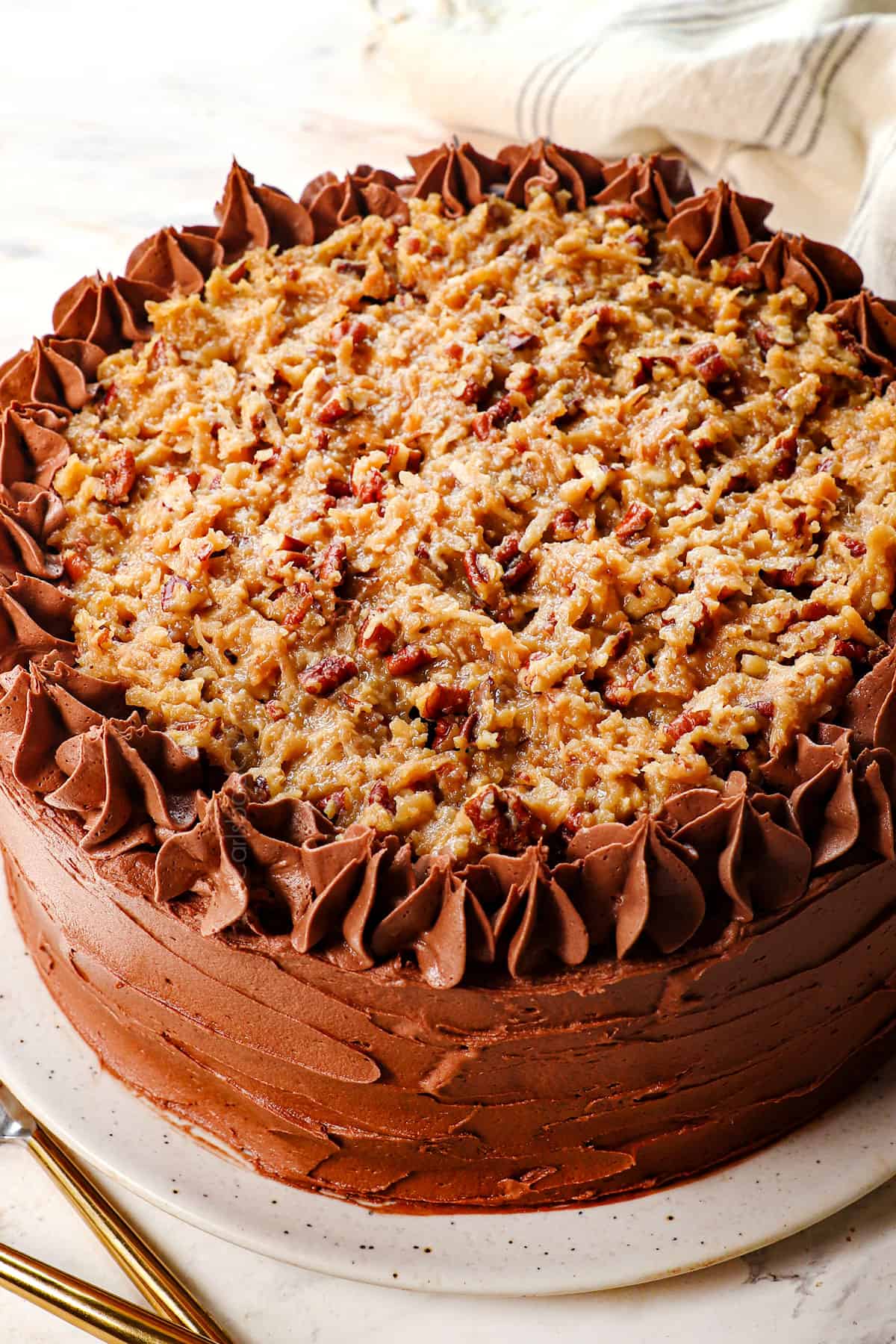 showing how to make German Chocolate Cake recipe by piping frosting along the top edge